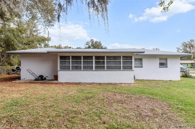 back of house with stucco siding and a yard