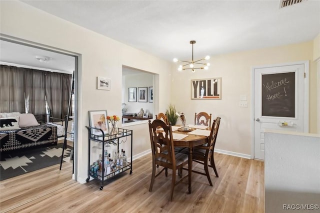 dining space with light wood-style floors, visible vents, baseboards, and an inviting chandelier