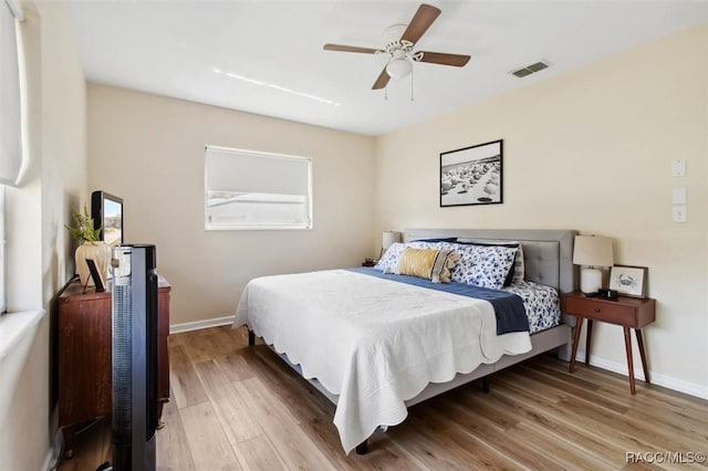 bedroom featuring light wood-type flooring, baseboards, visible vents, and ceiling fan