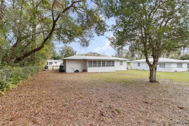 back of house featuring a fenced backyard and a lawn