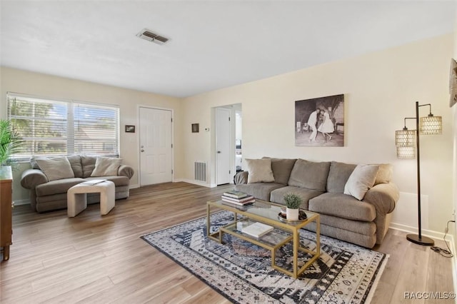 living room featuring light wood finished floors, baseboards, and visible vents