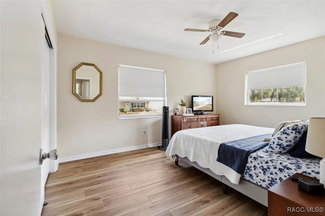 bedroom featuring a ceiling fan, light wood-type flooring, a closet, and baseboards