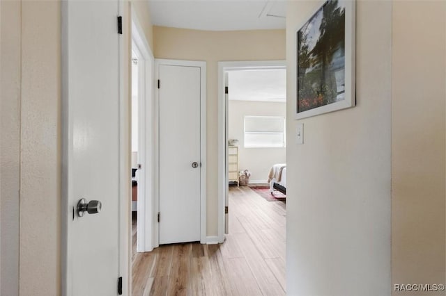 hallway featuring light wood finished floors and baseboards