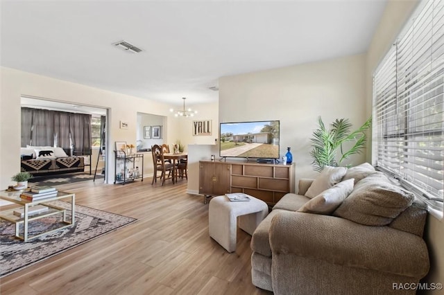 living room with light wood-type flooring, visible vents, and a notable chandelier