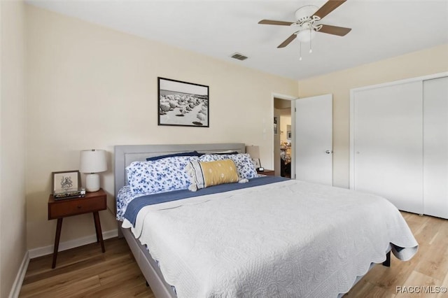 bedroom with baseboards, a closet, visible vents, and wood finished floors