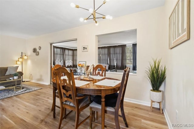 dining room with light wood-style flooring, baseboards, and a notable chandelier