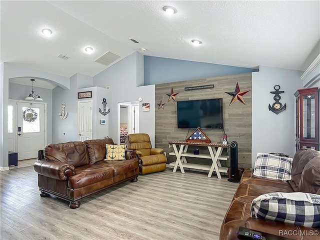 2478 W Angola Dr, Beverly Hills, FL 34465 - living room with light wood finished floors, arched walkways, high vaulted ceiling, a textured ceiling, and an accent wall