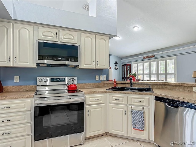 2478 W Angola Dr, Beverly Hills, FL 34465 - kitchen with stainless steel appliances, light tile patterned floors, lofted ceiling, light countertops, and white cabinets