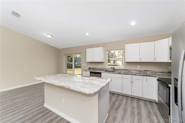 kitchen featuring white cabinets, a center island, and black stove