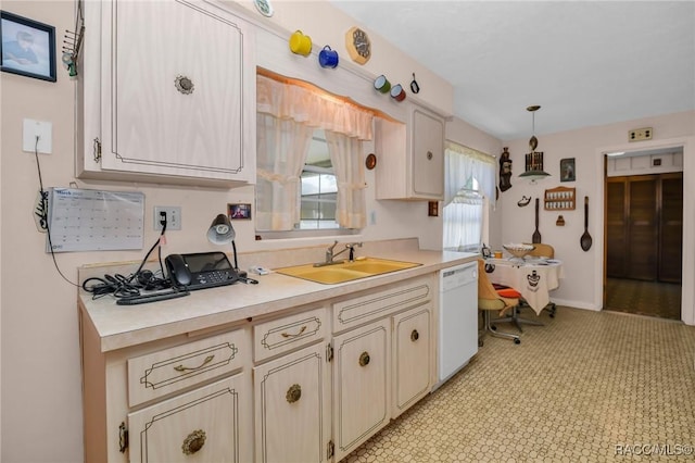 kitchen featuring pendant lighting, a sink, cream cabinets, white dishwasher, and light countertops