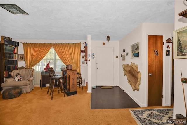 carpeted entrance foyer with visible vents, a textured ceiling, and baseboards