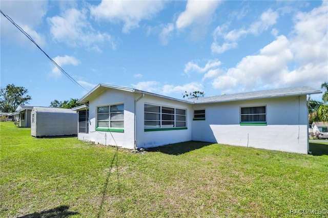 back of property with a yard and stucco siding