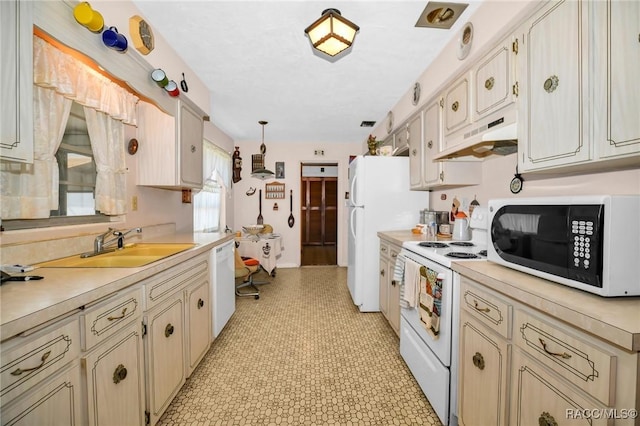 kitchen featuring cream cabinetry, under cabinet range hood, a sink, white appliances, and light countertops