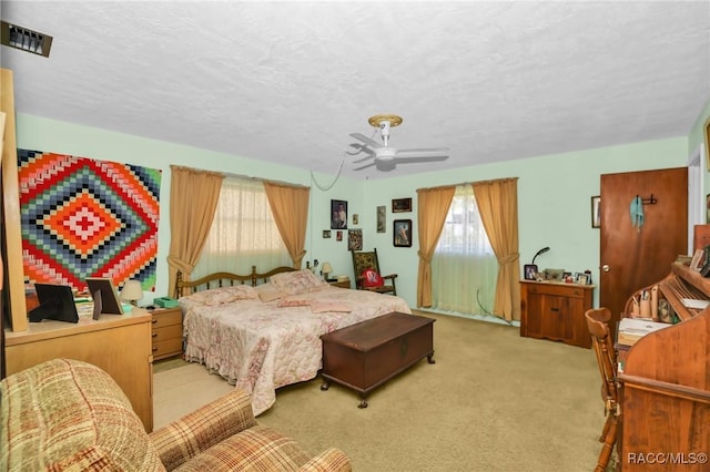 bedroom with visible vents, carpet floors, a textured ceiling, and ceiling fan