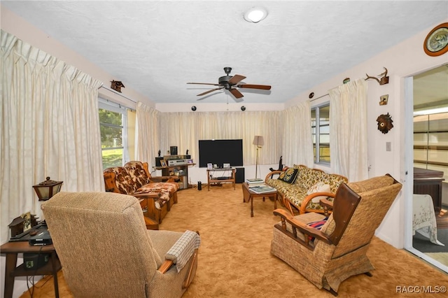 living area featuring light colored carpet, a textured ceiling, and ceiling fan