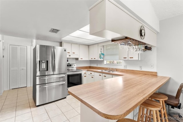 kitchen featuring white cabinetry, sink, stainless steel appliances, kitchen peninsula, and light tile patterned floors