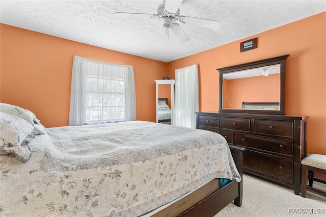 carpeted bedroom with ceiling fan and a textured ceiling