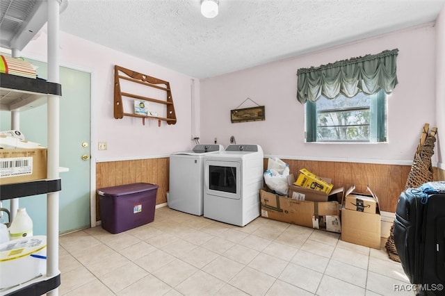 laundry room with washer and clothes dryer, light tile patterned floors, a textured ceiling, and wooden walls