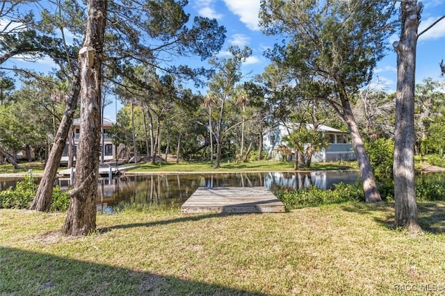 view of dock with a lawn and a water view