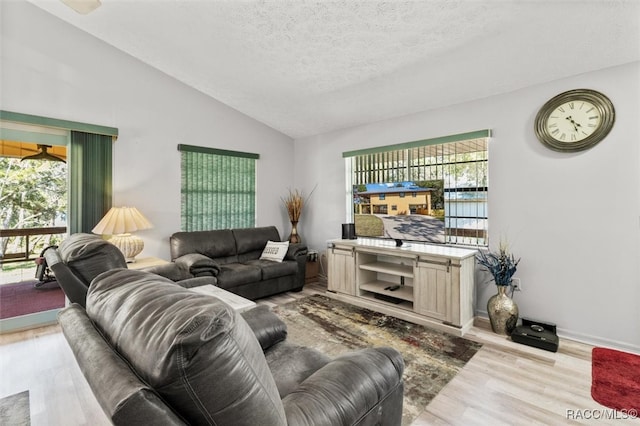 living room with light wood-type flooring, lofted ceiling, and a textured ceiling