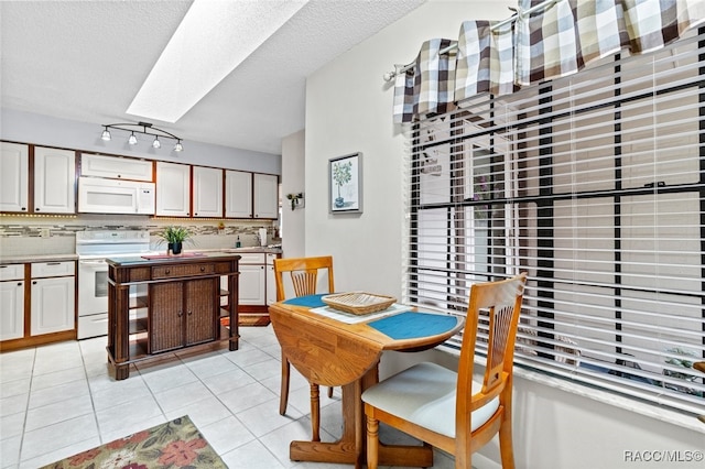 dining area with a skylight, sink, light tile patterned floors, and a textured ceiling