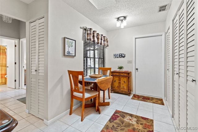 dining area with a textured ceiling and light tile patterned flooring