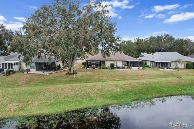 view of yard featuring a sunroom and a water view