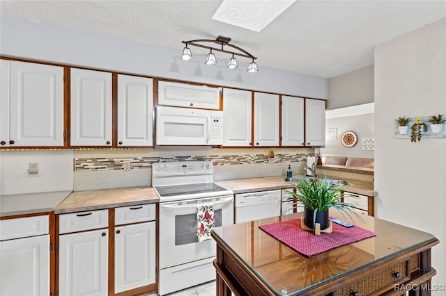 kitchen featuring white appliances, a skylight, white cabinetry, and sink