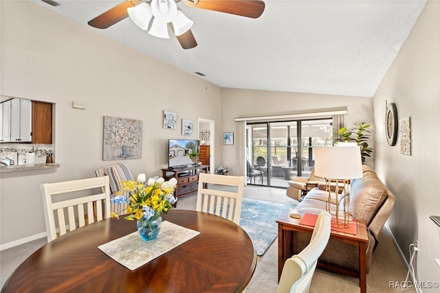 carpeted dining space featuring ceiling fan, high vaulted ceiling, and a textured ceiling