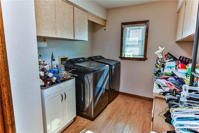 washroom with light hardwood / wood-style floors, cabinets, and washing machine and clothes dryer