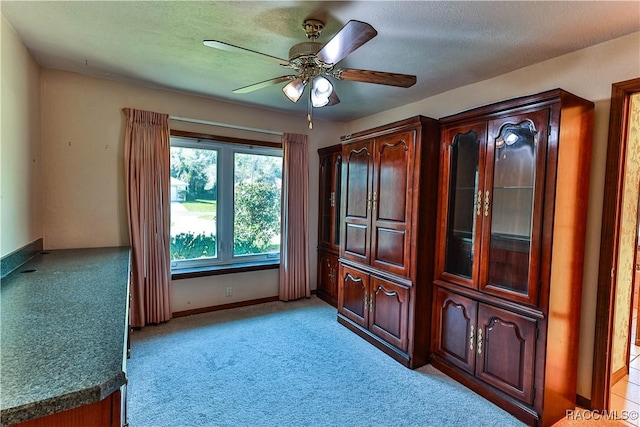 empty room with light carpet, ceiling fan, and a textured ceiling