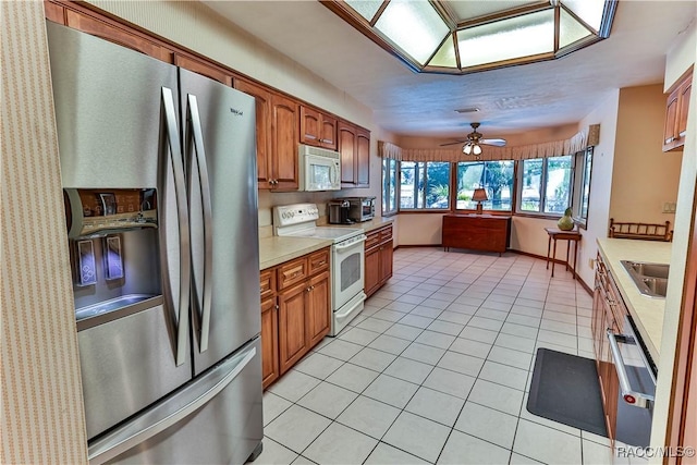 kitchen featuring ceiling fan, sink, light tile patterned flooring, and stainless steel appliances