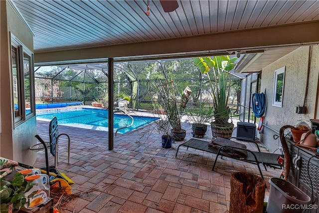 view of pool with glass enclosure and a patio