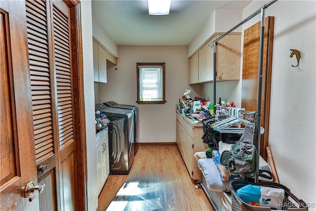 clothes washing area featuring cabinets, independent washer and dryer, and light hardwood / wood-style floors