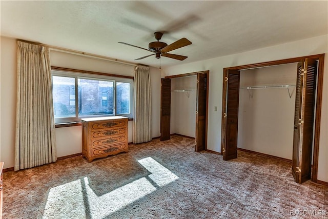 unfurnished bedroom featuring carpet flooring, ceiling fan, and two closets