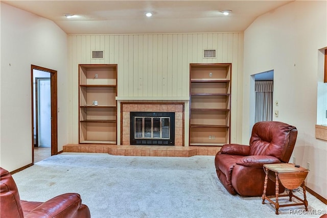 carpeted living room featuring a tile fireplace and built in features