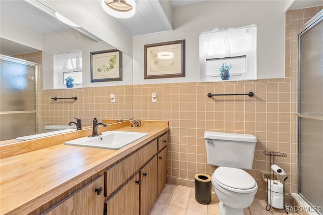 bathroom featuring tile patterned floors, vanity, tile walls, and toilet