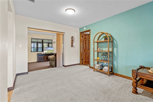 interior space featuring a textured ceiling and light carpet