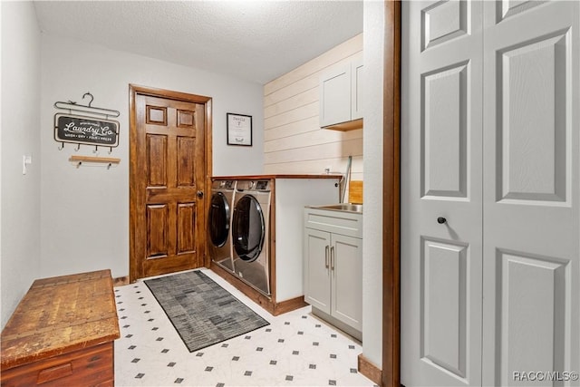 clothes washing area featuring cabinets, washer and dryer, and a textured ceiling