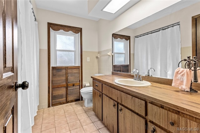 bathroom featuring tile patterned flooring, vanity, toilet, and tile walls