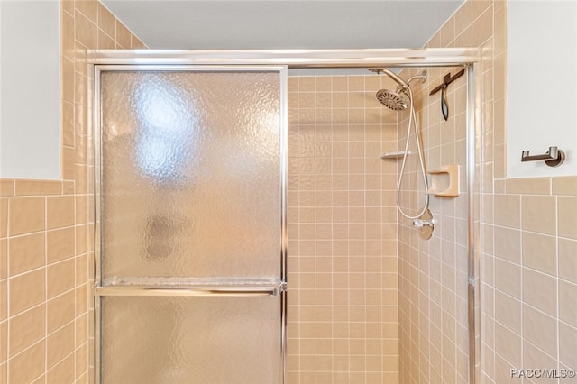 bathroom featuring tile walls and a shower with shower door