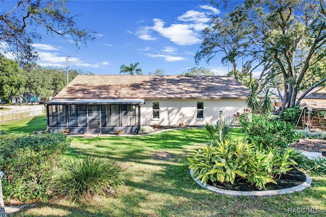 rear view of house featuring a yard and a sunroom