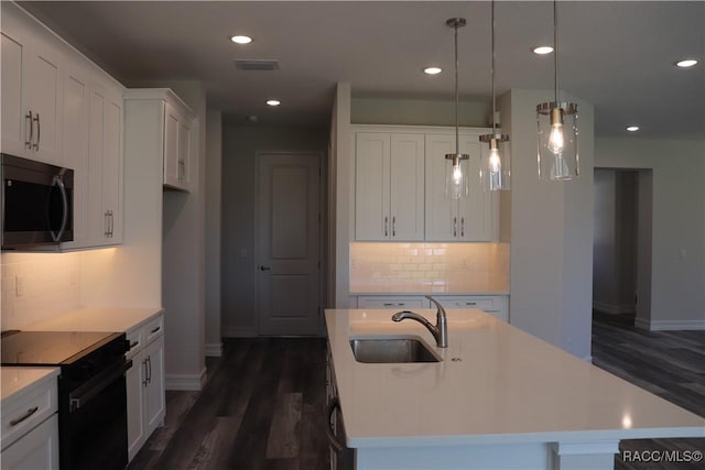 kitchen with a sink, visible vents, black electric range, stainless steel microwave, and an island with sink