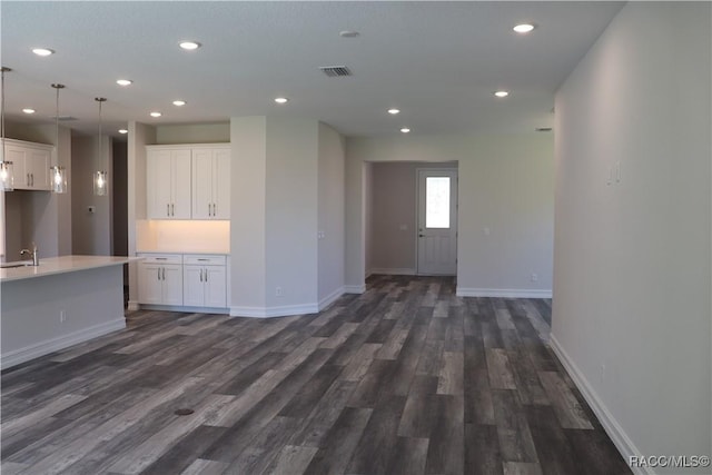 unfurnished living room featuring baseboards, visible vents, dark wood finished floors, and a sink