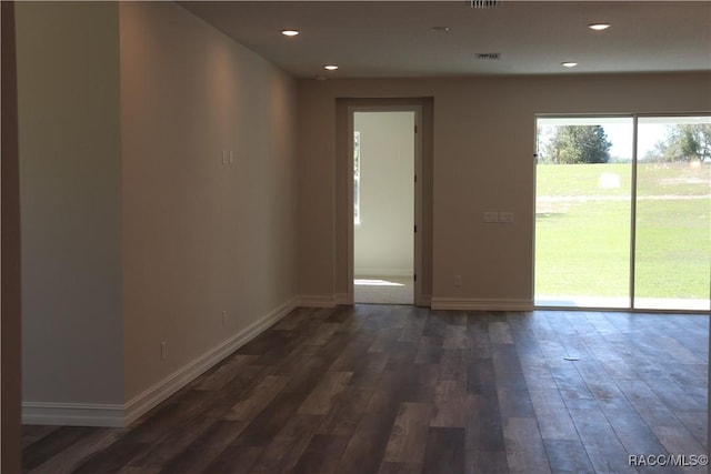 empty room featuring dark wood-style floors, recessed lighting, visible vents, and baseboards