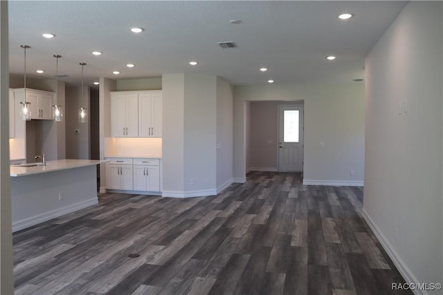 spare room featuring dark wood-style floors, baseboards, visible vents, and a sink