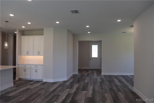 empty room with baseboards, dark wood-style flooring, visible vents, and recessed lighting