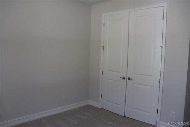 unfurnished bedroom featuring carpet, baseboards, and a closet