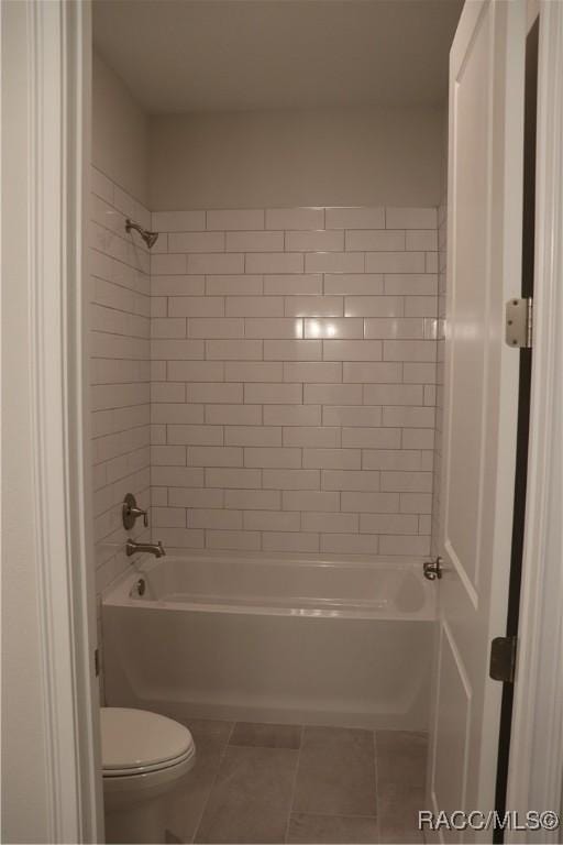 bathroom featuring toilet, tile patterned floors, and bathing tub / shower combination