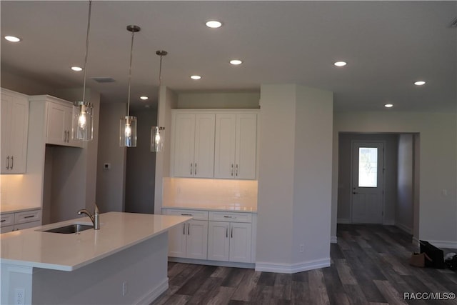 kitchen with tasteful backsplash, light countertops, dark wood-type flooring, white cabinetry, and a sink